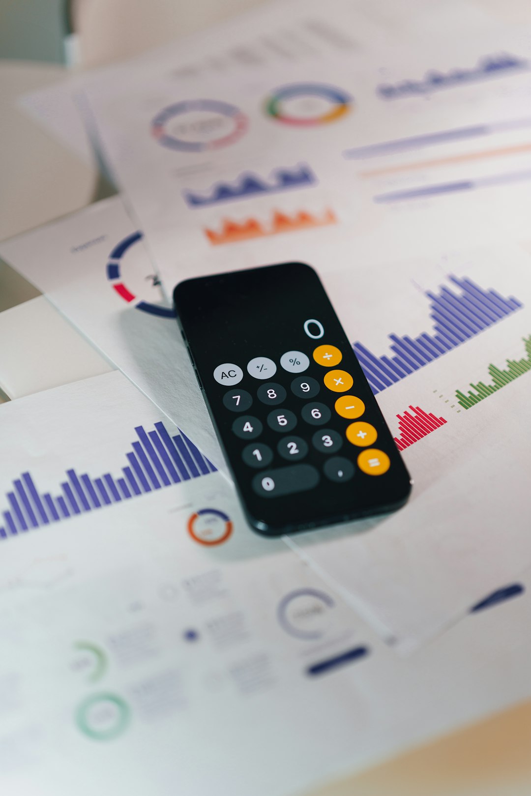 Photo by Jakub Żerdzicki smartphone calculator app on financial report papers