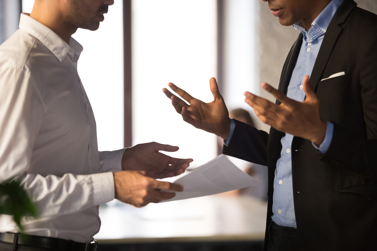 Close up executive manager dissatisfied by African American employee work Resolve commercial dispute